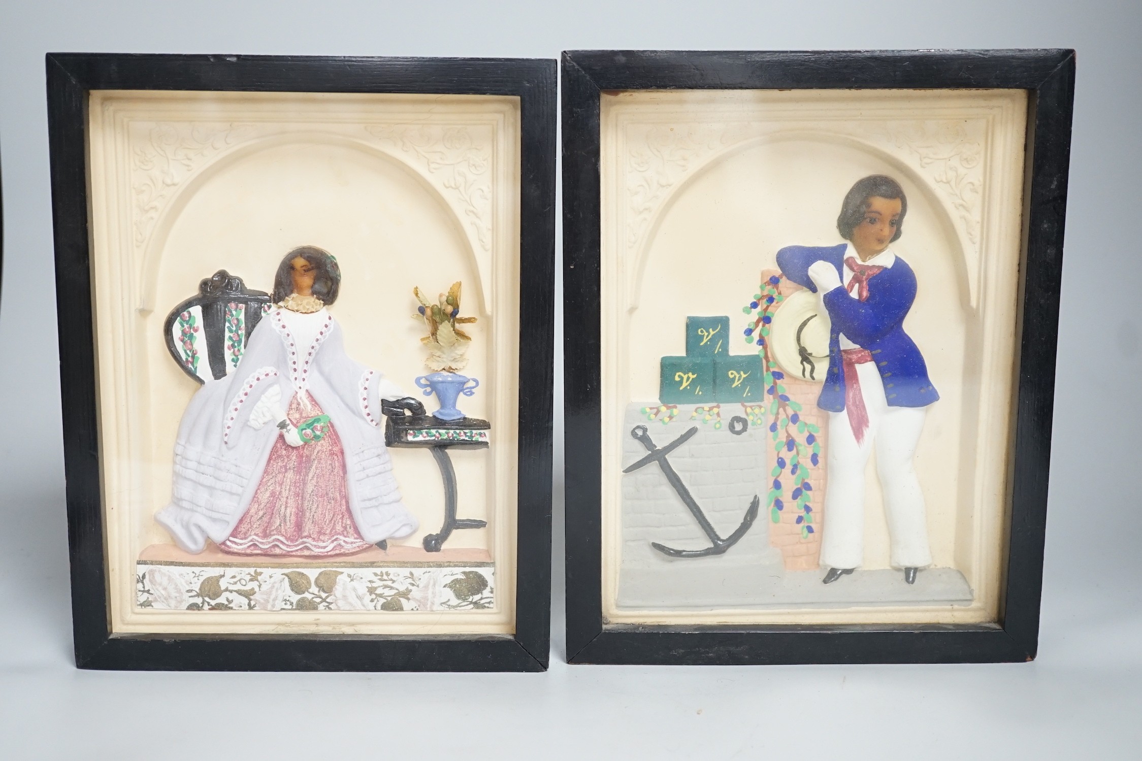 A pair of painted wax relief plaques, framed